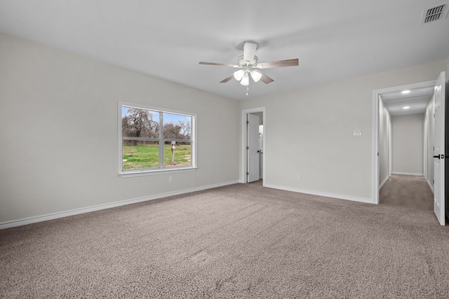 carpeted empty room featuring a ceiling fan, visible vents, and baseboards