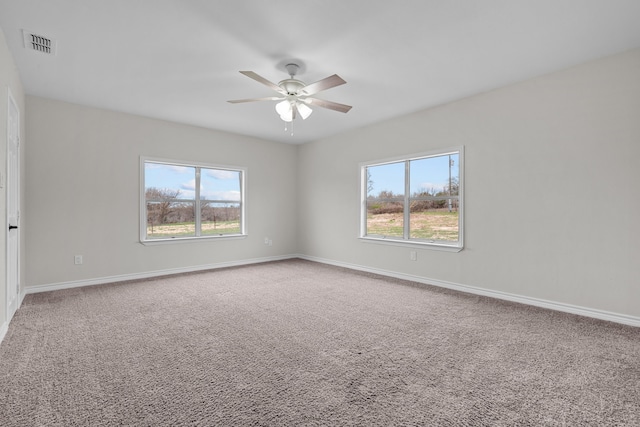 carpeted spare room featuring a ceiling fan, visible vents, and baseboards