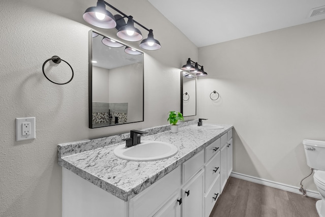 bathroom with baseboards, a sink, toilet, and wood finished floors