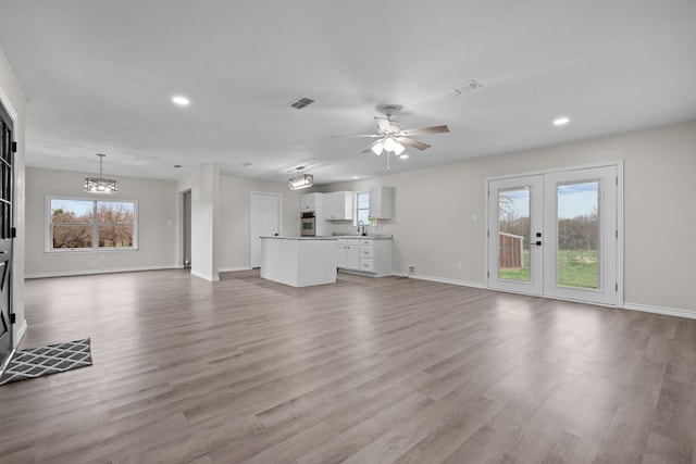 unfurnished living room with light wood-style floors, french doors, visible vents, and a sink