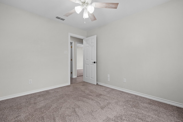 carpeted spare room with a ceiling fan, visible vents, and baseboards