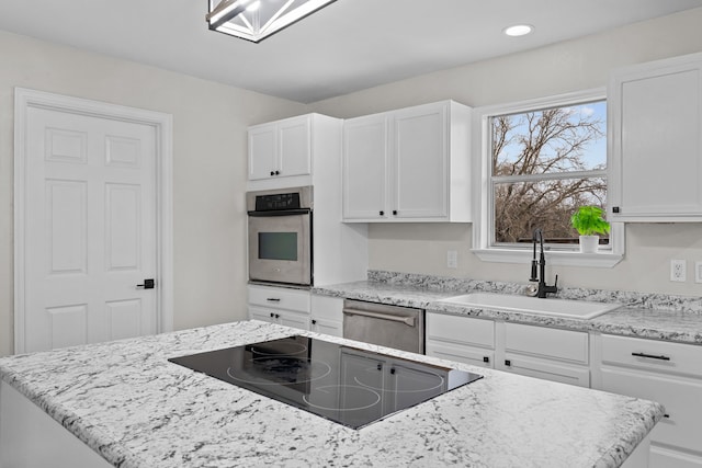 kitchen featuring light stone counters, stainless steel appliances, recessed lighting, white cabinets, and a sink