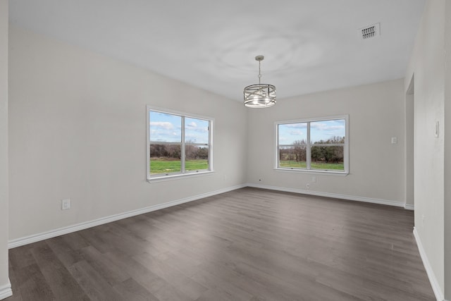 unfurnished room featuring baseboards, visible vents, a chandelier, and dark wood-type flooring