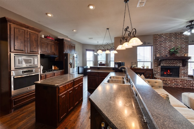 kitchen featuring sink, dark hardwood / wood-style flooring, stainless steel appliances, and a center island with sink