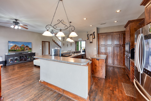 kitchen with a kitchen island with sink, dark hardwood / wood-style flooring, hanging light fixtures, and appliances with stainless steel finishes