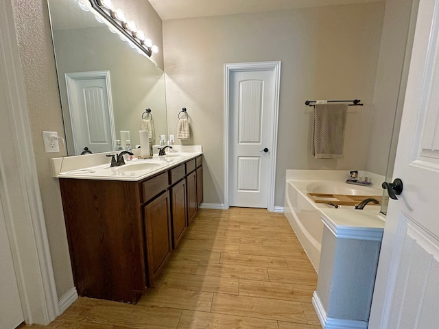 bathroom with wood-type flooring, dual vanity, and a tub to relax in