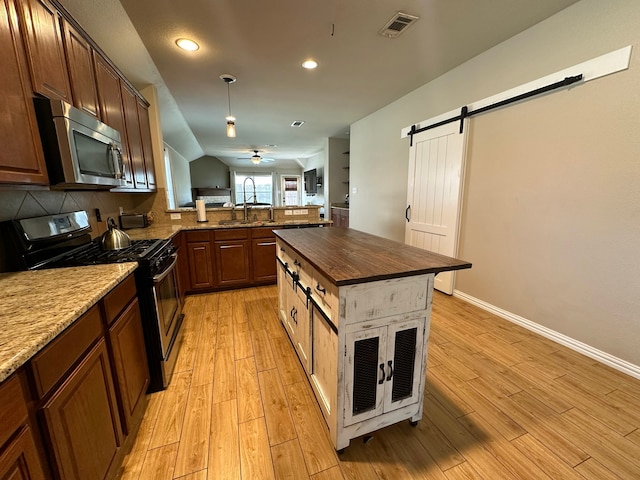 kitchen with electric range oven, a barn door, light hardwood / wood-style floors, decorative backsplash, and ceiling fan