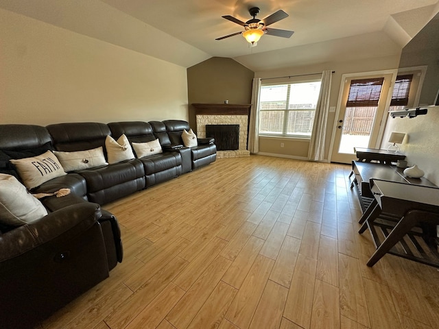 living room featuring a fireplace, lofted ceiling, light wood-type flooring, and ceiling fan