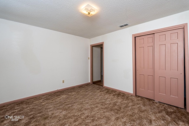 unfurnished bedroom featuring carpet, a textured ceiling, and a closet