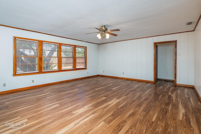 empty room featuring ornamental molding, dark wood-type flooring, a textured ceiling, and ceiling fan