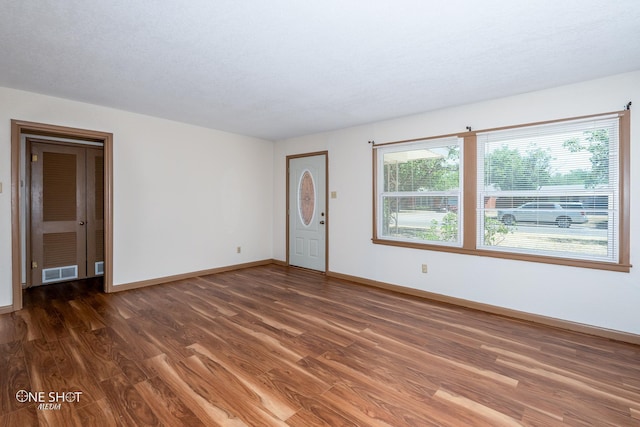 spare room featuring a textured ceiling and dark hardwood / wood-style flooring