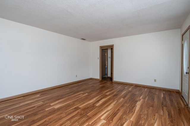 empty room featuring dark hardwood / wood-style flooring and a textured ceiling