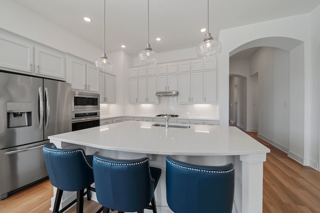 kitchen featuring a kitchen island with sink, pendant lighting, white cabinets, and appliances with stainless steel finishes