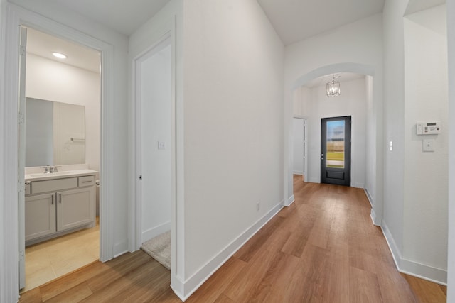 corridor with sink and light hardwood / wood-style flooring