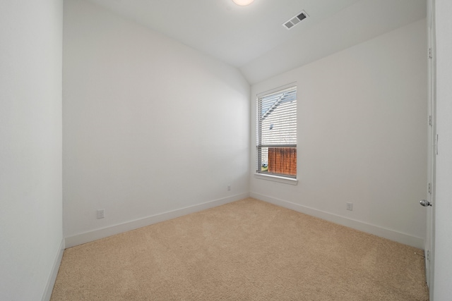 carpeted spare room featuring vaulted ceiling