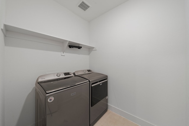 clothes washing area featuring light tile patterned floors and washer and dryer