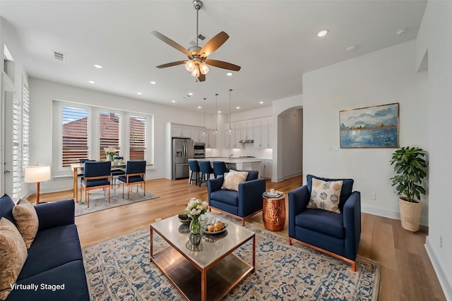 living room featuring arched walkways, recessed lighting, and light wood-style floors