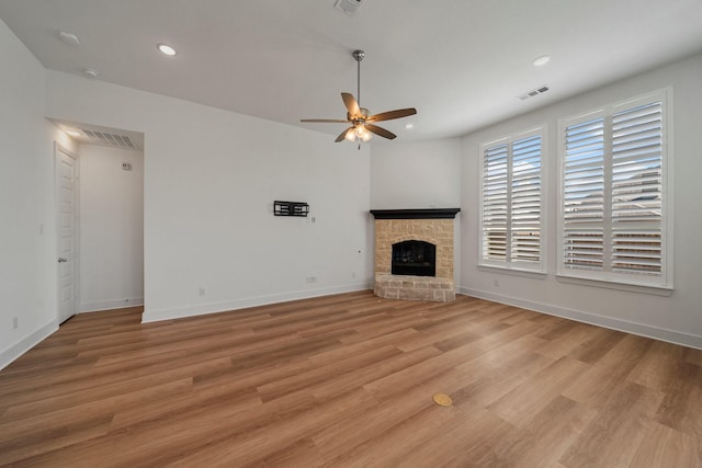 unfurnished living room with visible vents, a fireplace with raised hearth, ceiling fan, light wood-type flooring, and recessed lighting