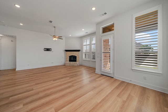 unfurnished living room featuring light wood-type flooring, ceiling fan, a fireplace, and visible vents