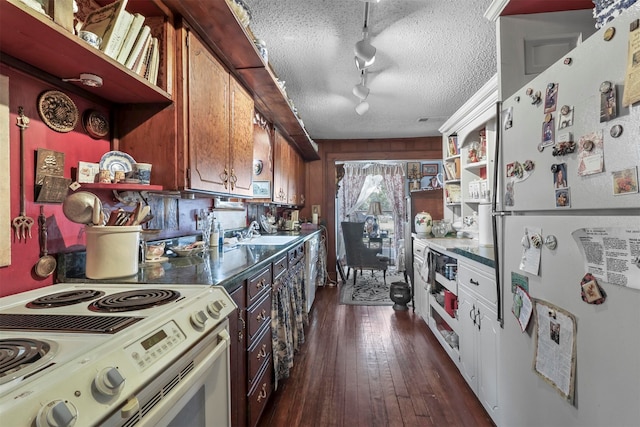 kitchen featuring track lighting, white appliances, sink, a textured ceiling, and dark wood-type flooring