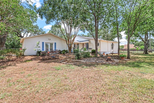 rear view of property with french doors and a lawn