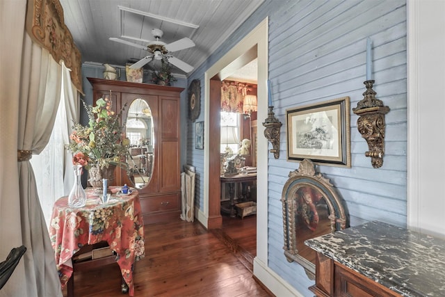 entrance foyer with ornamental molding, dark hardwood / wood-style flooring, ceiling fan, and wooden walls