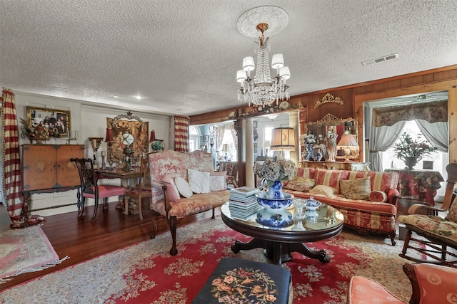 living room featuring an inviting chandelier, wood-type flooring, and a textured ceiling