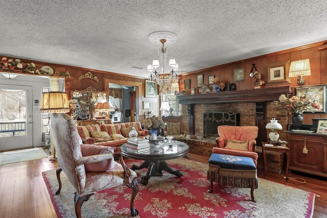 living room with a textured ceiling, wood-type flooring, a brick fireplace, and plenty of natural light