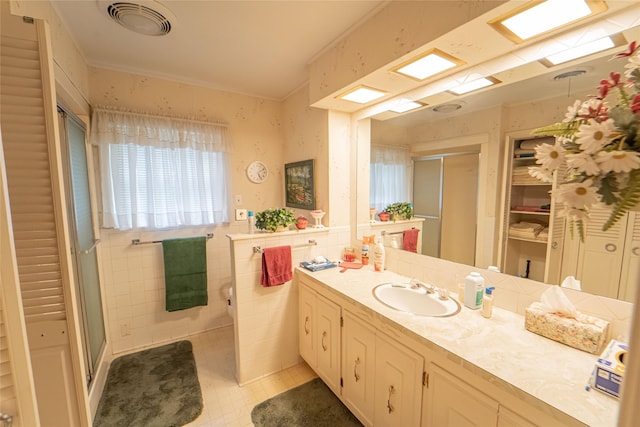 bathroom featuring walk in shower, vanity, and tile walls