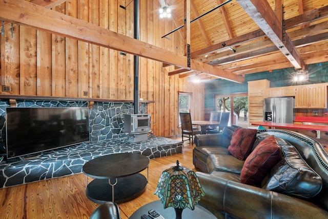 living room featuring wood-type flooring, a wood stove, lofted ceiling with beams, wood walls, and wood ceiling