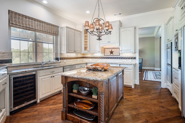 kitchen featuring white cabinets, decorative light fixtures, a kitchen island, and beverage cooler