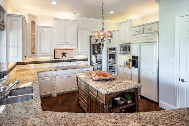 kitchen with dark hardwood / wood-style flooring, sink, pendant lighting, built in appliances, and white cabinets