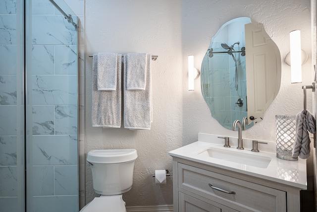 bathroom with tiled shower, vanity, and toilet