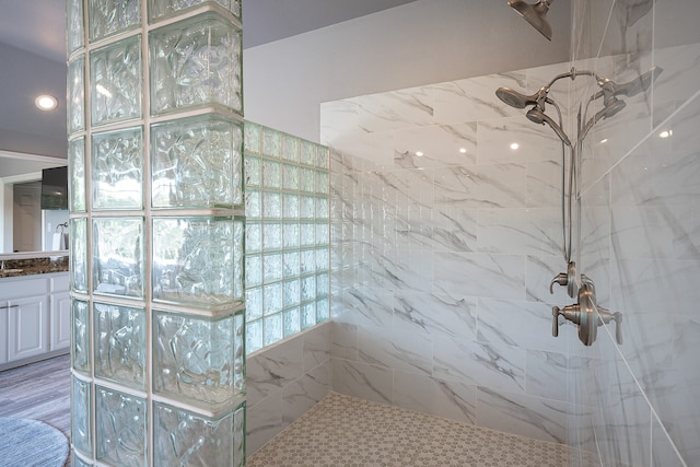 bathroom with tiled shower, vanity, and hardwood / wood-style flooring