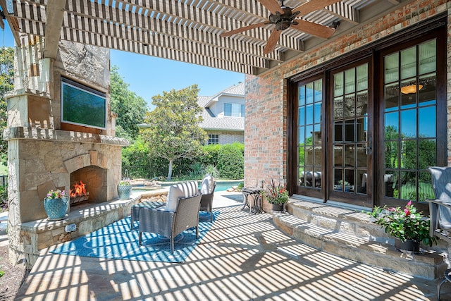 view of patio with an outdoor stone fireplace and ceiling fan