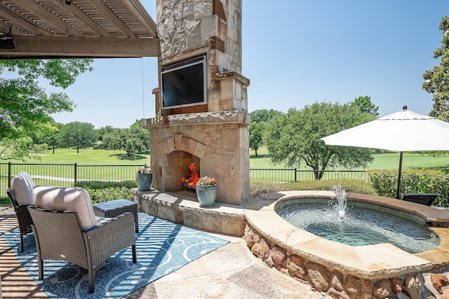 view of patio / terrace with pool water feature and an outdoor stone fireplace