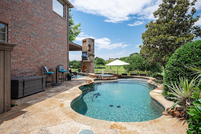 view of pool featuring an in ground hot tub, an outdoor stone fireplace, and a patio