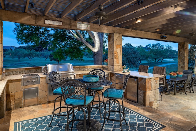 view of patio / terrace featuring a grill, ceiling fan, exterior bar, and an outdoor kitchen