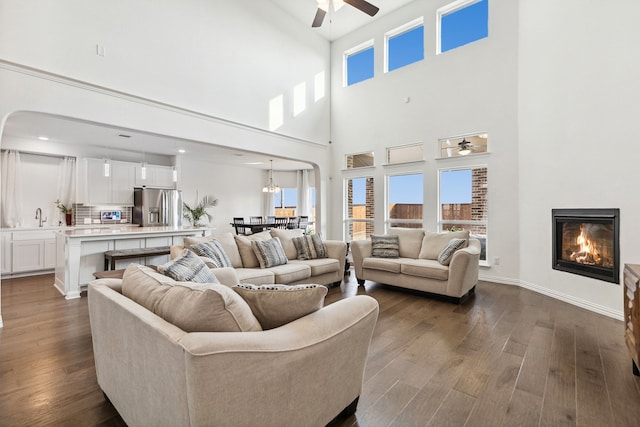 living room with ceiling fan, sink, a high ceiling, and hardwood / wood-style floors