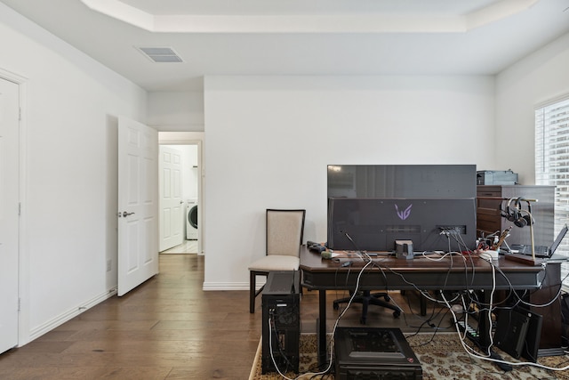 office area with dark wood-type flooring, a raised ceiling, and washer / clothes dryer