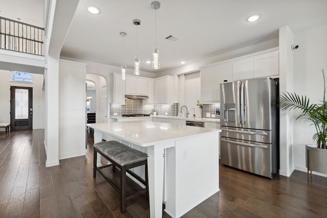 kitchen with white cabinetry, stainless steel appliances, dark hardwood / wood-style flooring, and a kitchen island