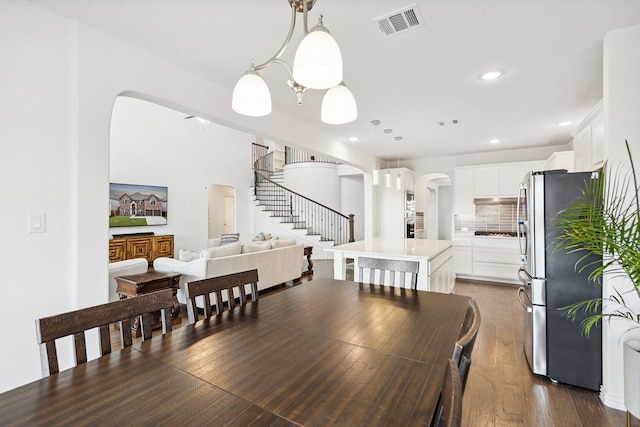 dining space featuring dark wood-type flooring and an inviting chandelier