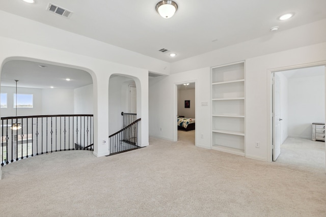 empty room featuring light colored carpet and built in features