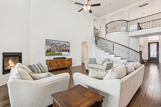 living room featuring ceiling fan, a towering ceiling, and dark hardwood / wood-style flooring