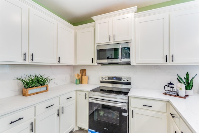 kitchen featuring tasteful backsplash, white cabinetry, appliances with stainless steel finishes, and light stone countertops