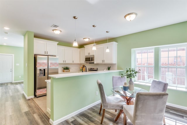 kitchen featuring hanging light fixtures, white cabinetry, appliances with stainless steel finishes, and plenty of natural light