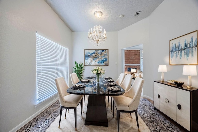 dining area with a notable chandelier, light colored carpet, and a textured ceiling