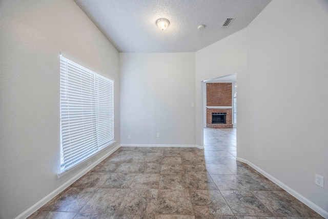 unfurnished room with a fireplace and a textured ceiling