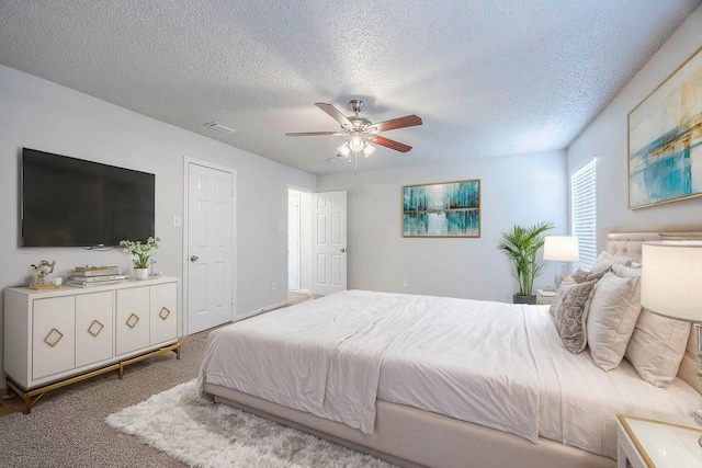 carpeted bedroom with ceiling fan and a textured ceiling