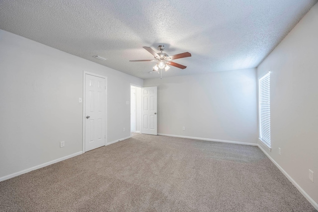 carpeted spare room with plenty of natural light, ceiling fan, and a textured ceiling